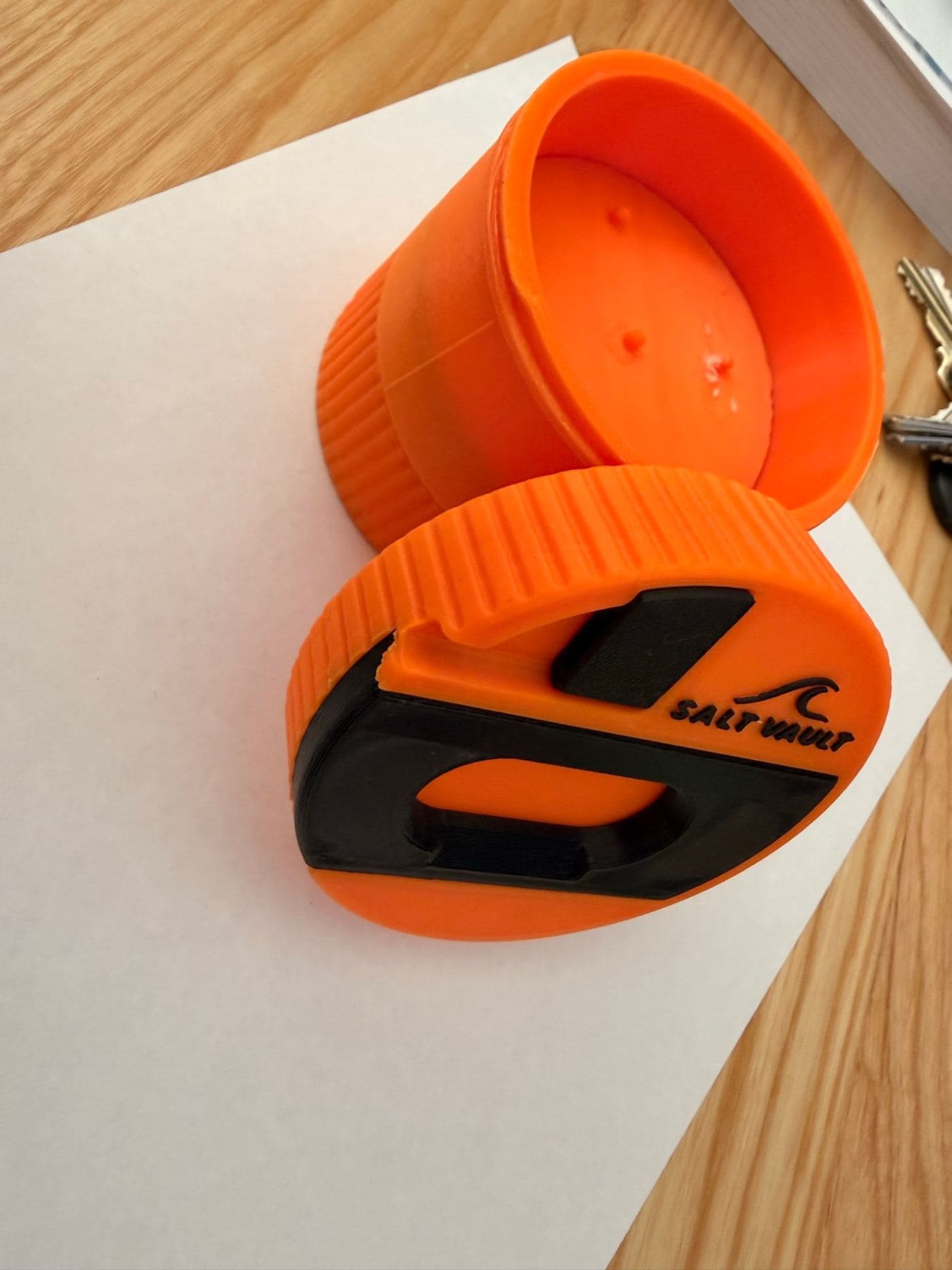 An early 3D-printed Salt Vault prototype on the workbench — orange tub and lid with the black scraper plate
